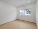 Spacious bedroom with wooden flooring and large window