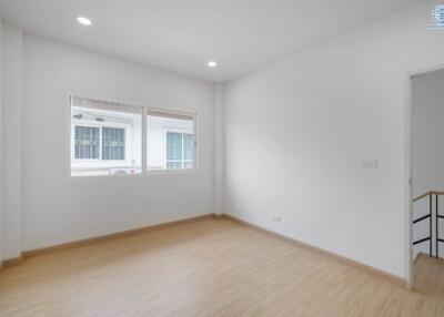 Spacious bedroom with wooden flooring and large windows