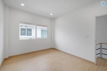 Spacious bedroom with wooden flooring and large windows