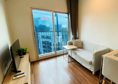 Modern living room with a couch, TV, and balcony view