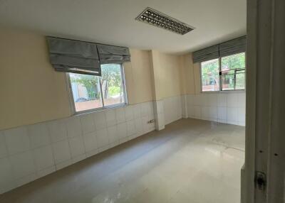 Empty room with tiled walls, two windows, and fluorescent lighting