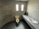 Modern minimalist bathroom with toilet, sink, and concrete finish