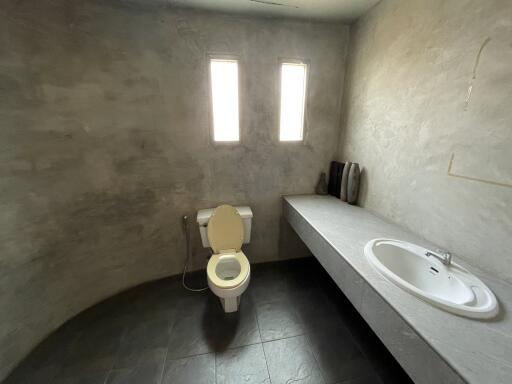 Modern minimalist bathroom with toilet, sink, and concrete finish