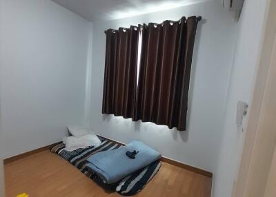 Small bedroom with air mattress and window with brown curtains