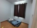 Small bedroom with air mattress and window with brown curtains