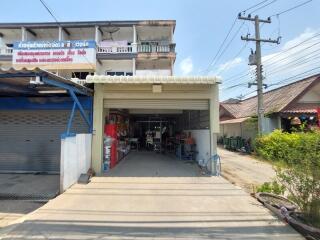 Exterior view of a commercial building with garage and adjacent shops