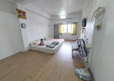 Spacious bedroom with bed, wall-mounted TV, and fan