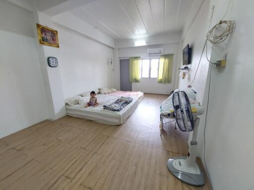 Spacious bedroom with bed, wall-mounted TV, and fan