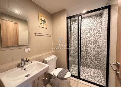 Modern bathroom with sink, toilet, and shower area featuring patterned tiles