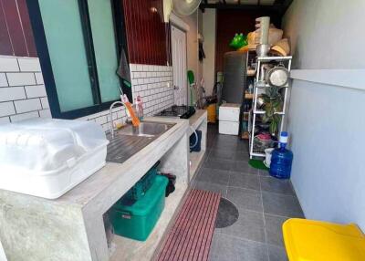 An outdoor kitchen with concrete counters, a sink, and storage shelves.