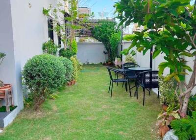 Side garden with lawn, bushes, trees, and outdoor seating