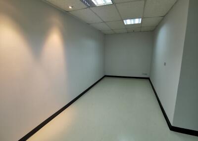 Empty room with white walls, ceiling lights, and white tiled floor