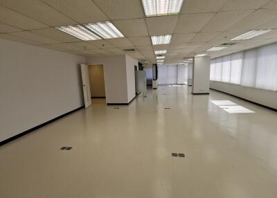 Spacious and well-lit commercial area with tiled flooring and fluorescent lighting