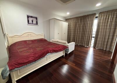 Spacious bedroom with wooden floor and large windows