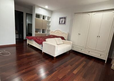 Spacious bedroom with wooden flooring, bed, wardrobe, and ambient lighting.