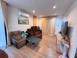 Modern living room with sofa, recliner, air conditioner, and large television