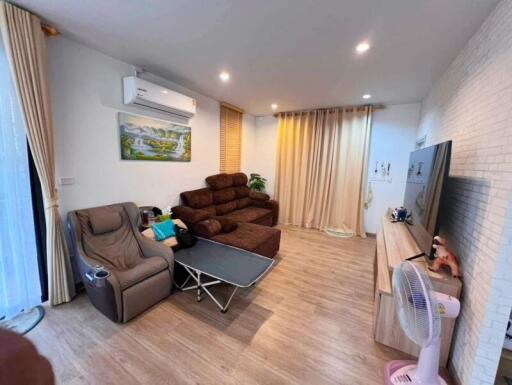 Modern living room with sofa, recliner, air conditioner, and large television