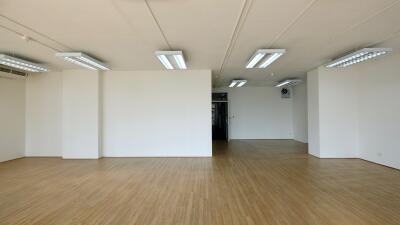 Spacious empty room with wooden flooring and white walls