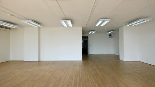 Spacious empty room with wooden flooring and white walls