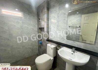 Modern bathroom with tiled walls and floor, equipped with a toilet and sink