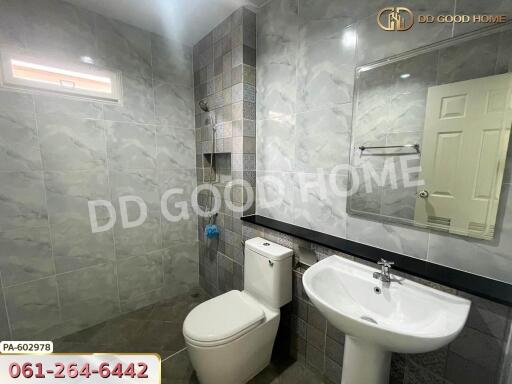 Modern bathroom with tiled walls and floor, equipped with a toilet and sink