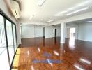 Spacious open-plan living area with wooden flooring and large windows