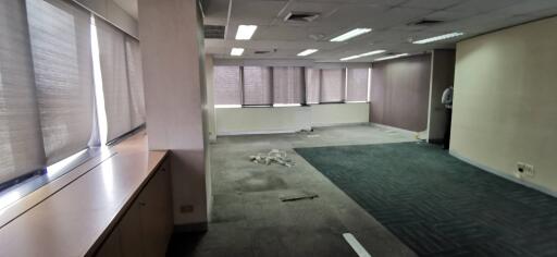 Empty office space with large windows and carpet flooring