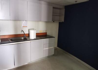 Modern kitchen area with white cabinetry and dark countertops