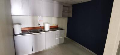 Modern kitchen area with white cabinetry and dark countertops