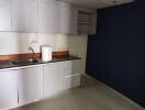 Modern kitchen area with white cabinetry and dark countertops