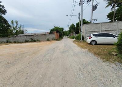 Gravel road with a parked white car and surrounding fences