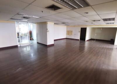 Spacious empty office space with hardwood flooring and large windows