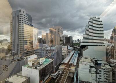 View of cityscape with multiple buildings and rail tracks under a cloudy sky