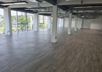 Spacious open-plan office area with large windows and wooden flooring