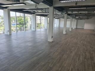 Spacious open-plan office area with large windows and wooden flooring