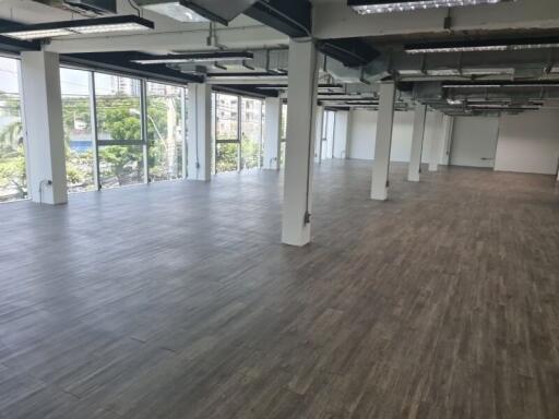 Spacious open office area with large windows and wooden flooring