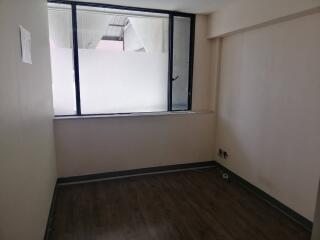 Empty room with large window and wooden flooring