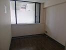 Empty room with large window and wooden flooring