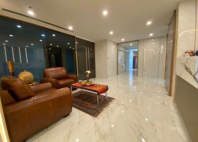 Modern living room with marble flooring, leather couches, and glass partitions