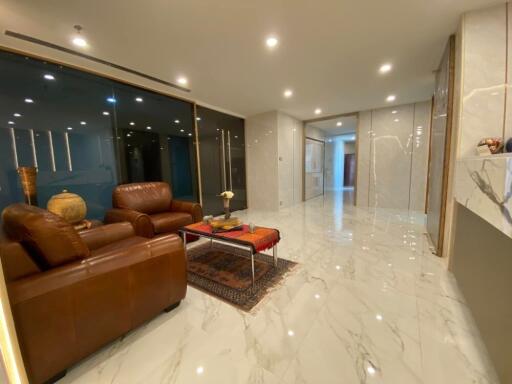 Modern living room with marble flooring, leather couches, and glass partitions