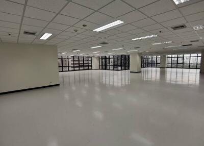 Spacious empty office space with large windows and white floor