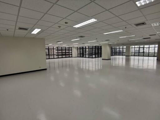 Spacious empty office space with large windows and white floor