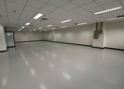 Spacious empty commercial area with tiled floor and ceiling lighting