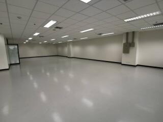 Spacious empty commercial area with tiled floor and ceiling lighting