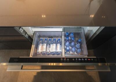 Modern kitchen with built-in fridge drawer open showing bottled beverages