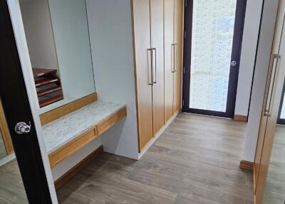 Modern walk-in closet with wooden cabinetry and large mirror