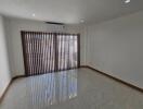 Spacious unfurnished living room with large windows and air conditioning.