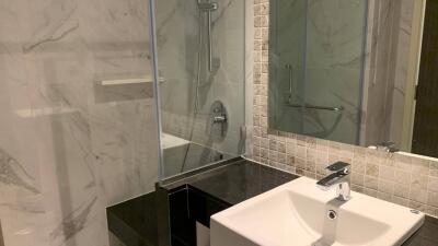 Modern bathroom with sink, shower, and marble tiles