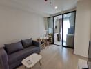 Modern living room with a sofa, coffee table, dining set, and view of the kitchen