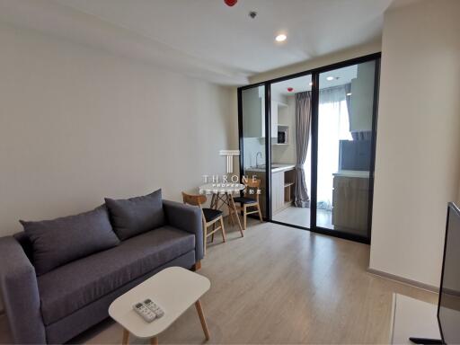 Modern living room with a sofa, coffee table, dining set, and view of the kitchen